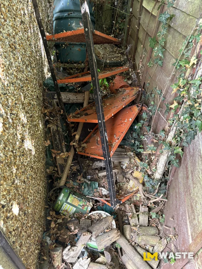 Before: Side passage: old shelving, timber, pots and the ivy pulled out, water butt left where it was