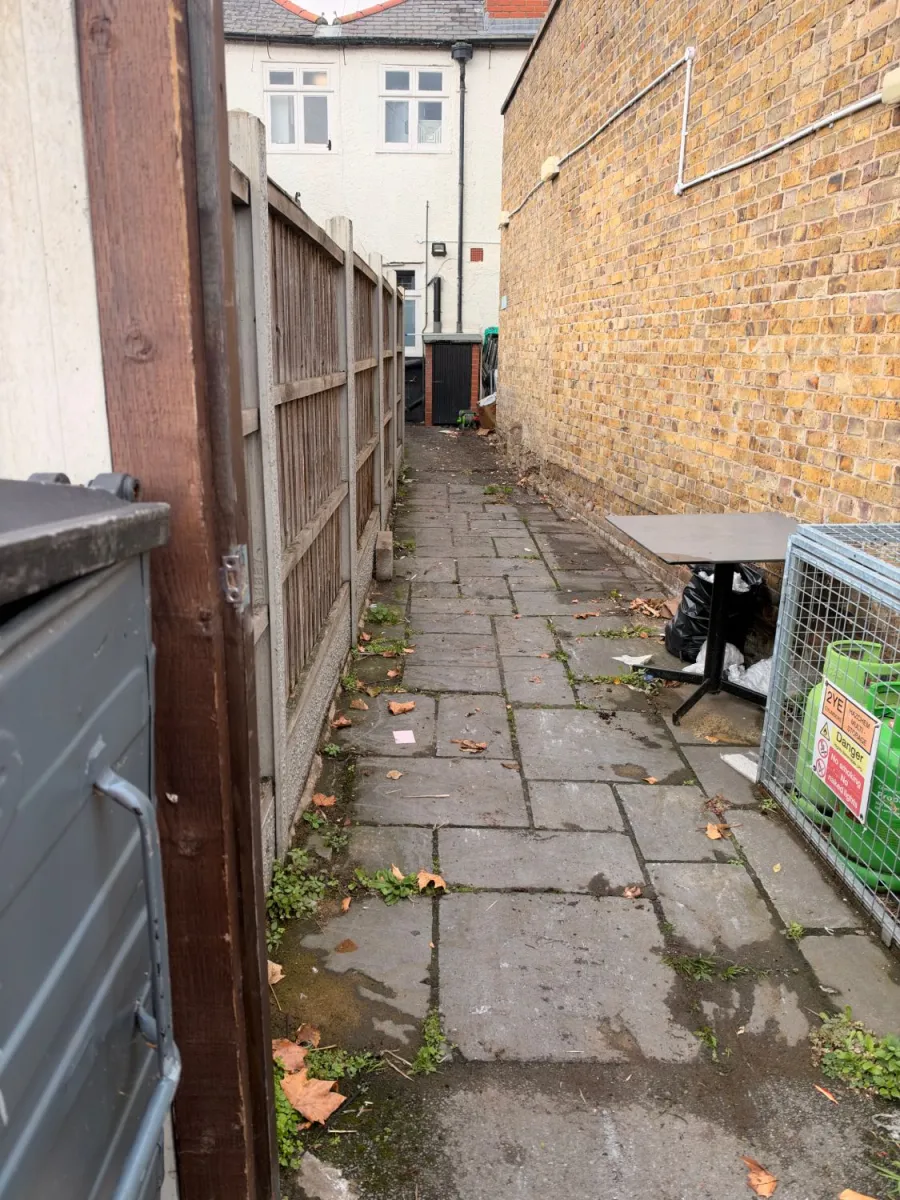 After: Rear passage clearance: overgrown planters, an old table and loose rubbish removed, gas cage left in place